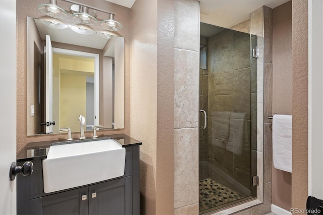 bathroom with a stall shower, a textured wall, and vanity
