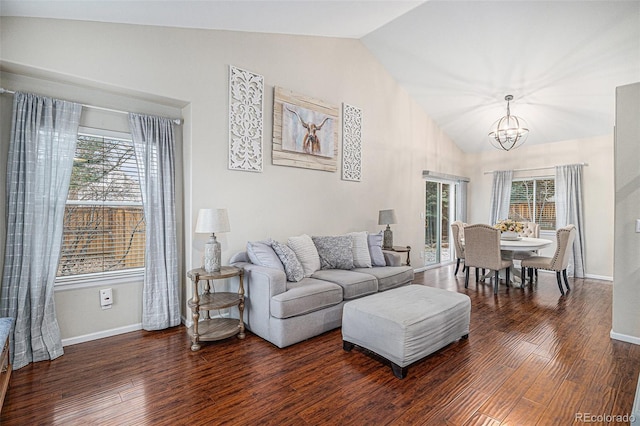 living room with an inviting chandelier, plenty of natural light, dark hardwood / wood-style flooring, and vaulted ceiling