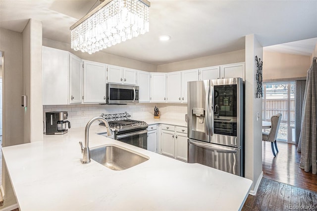 kitchen with stainless steel appliances, kitchen peninsula, sink, and white cabinets