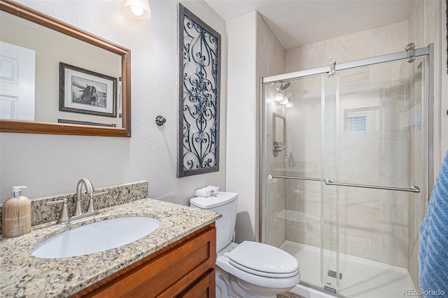 bathroom with a shower with door, vanity, and toilet