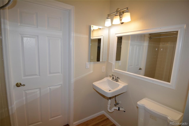 bathroom featuring hardwood / wood-style floors, toilet, walk in shower, and sink