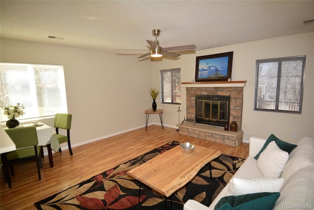 living area with baseboards, visible vents, wood finished floors, a textured ceiling, and a fireplace