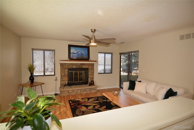 living room featuring plenty of natural light, visible vents, a fireplace, and wood finished floors