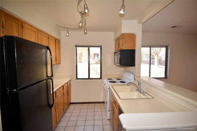 kitchen featuring light tile patterned floors, light countertops, a sink, black appliances, and baseboards