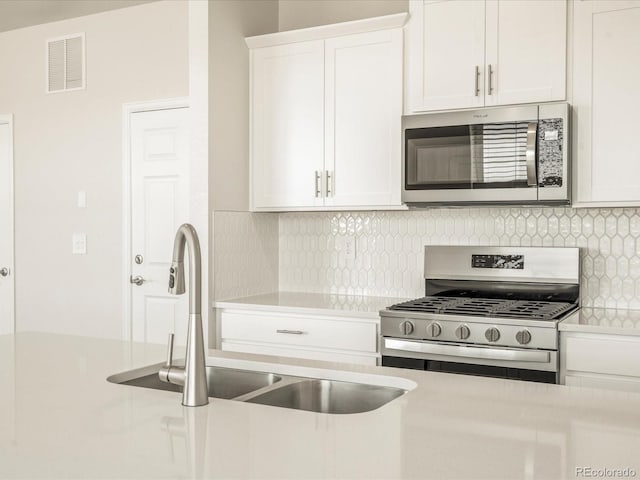 kitchen featuring tasteful backsplash, white cabinetry, sink, and stainless steel appliances