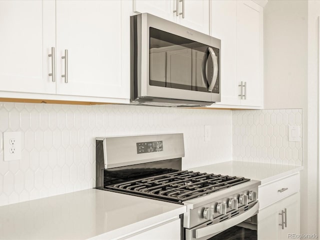 kitchen with white cabinets, appliances with stainless steel finishes, and backsplash