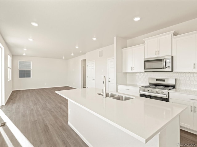 kitchen with a center island with sink, white cabinets, light hardwood / wood-style flooring, sink, and appliances with stainless steel finishes