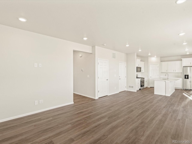 unfurnished living room featuring wood-type flooring and sink