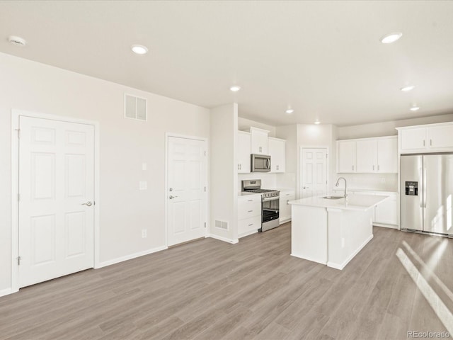 kitchen featuring white cabinetry, light wood-type flooring, stainless steel appliances, and a center island with sink