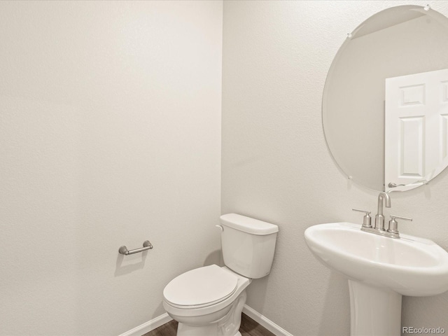 bathroom featuring toilet, sink, and wood-type flooring