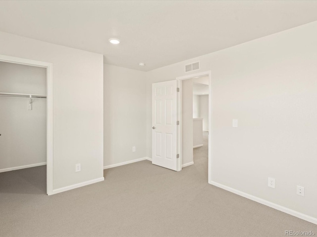 unfurnished bedroom with a closet, a walk in closet, and carpet flooring