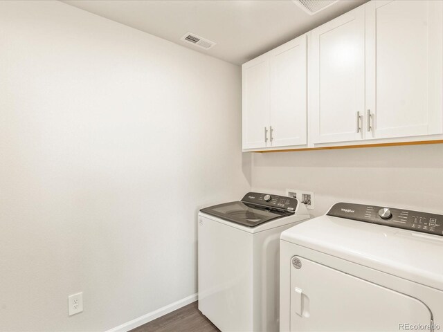 washroom with dark hardwood / wood-style flooring, washing machine and dryer, and cabinets