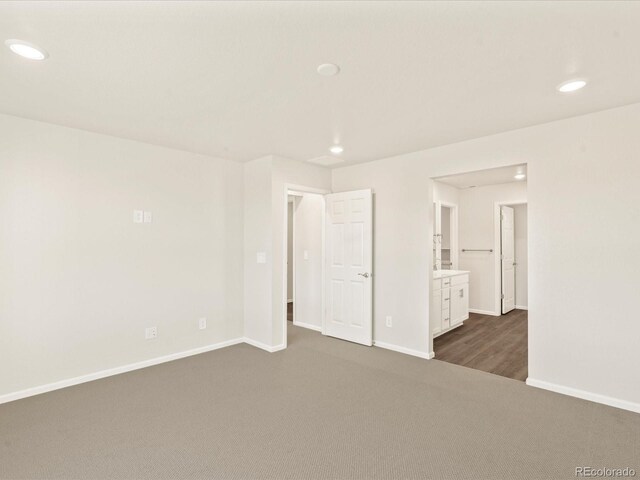 unfurnished bedroom featuring ensuite bath and dark carpet