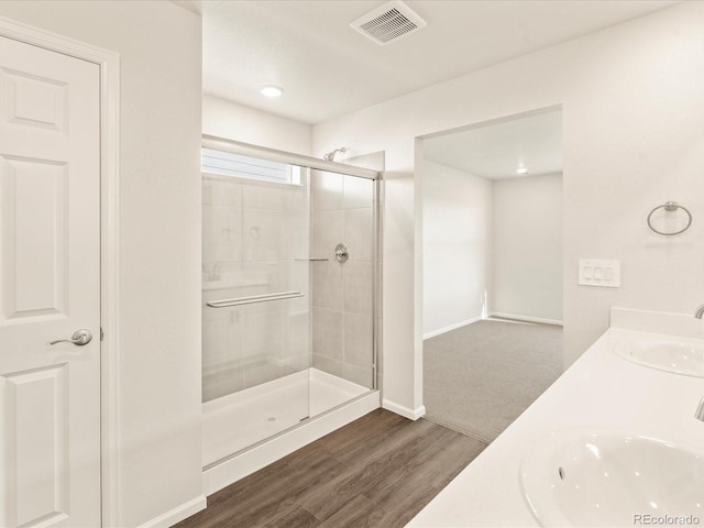 bathroom with wood-type flooring, vanity, and a shower with door