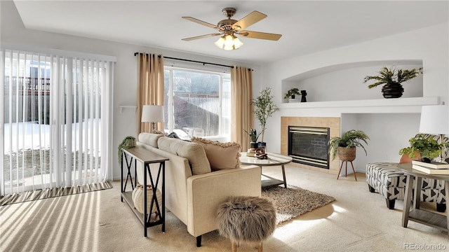 living room featuring light carpet, a tile fireplace, and ceiling fan