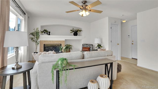 living room featuring light carpet, a tile fireplace, and ceiling fan