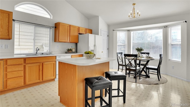 kitchen with lofted ceiling, sink, decorative light fixtures, a center island, and white appliances