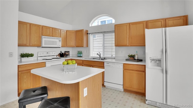 kitchen featuring a kitchen bar, sink, high vaulted ceiling, a kitchen island, and white appliances