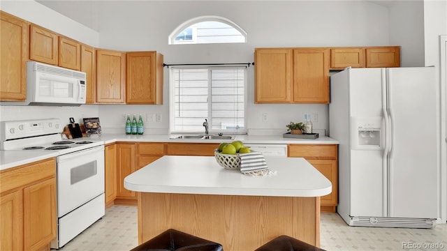 kitchen featuring sink, white appliances, a center island, and a healthy amount of sunlight