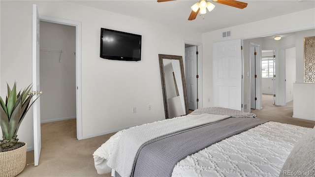 bedroom with ceiling fan, a spacious closet, light carpet, and a closet