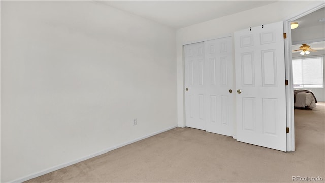 unfurnished bedroom with light colored carpet and a closet