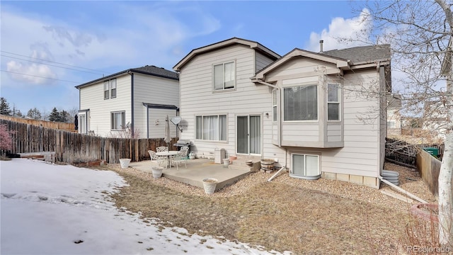 snow covered rear of property with a patio