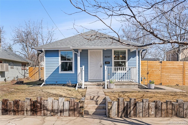 view of front of house featuring a porch, a fenced front yard, and roof with shingles