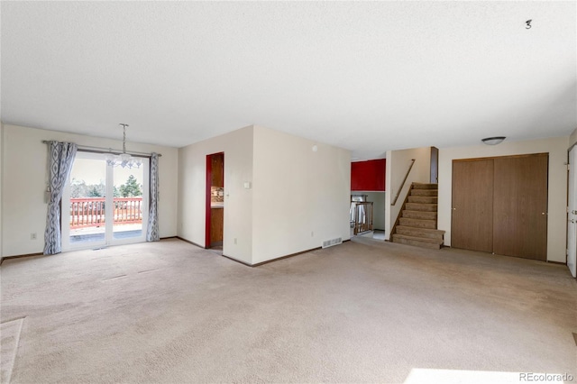 unfurnished living room featuring visible vents, a textured ceiling, stairway, carpet flooring, and baseboards