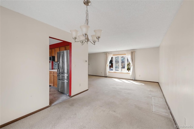 empty room featuring a textured ceiling, an inviting chandelier, baseboards, and light carpet