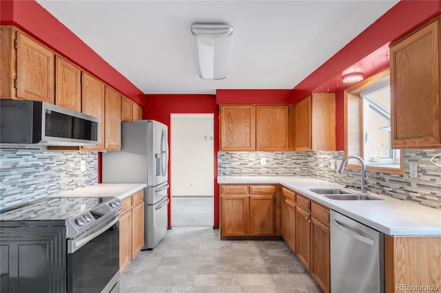 kitchen with a sink, light countertops, appliances with stainless steel finishes, brown cabinets, and backsplash