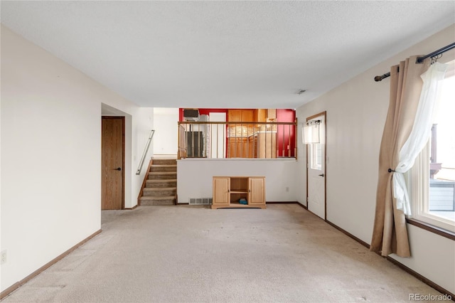 unfurnished living room featuring stairs, carpet, visible vents, and baseboards