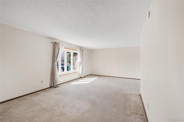 empty room featuring carpet flooring, a textured ceiling, and baseboards