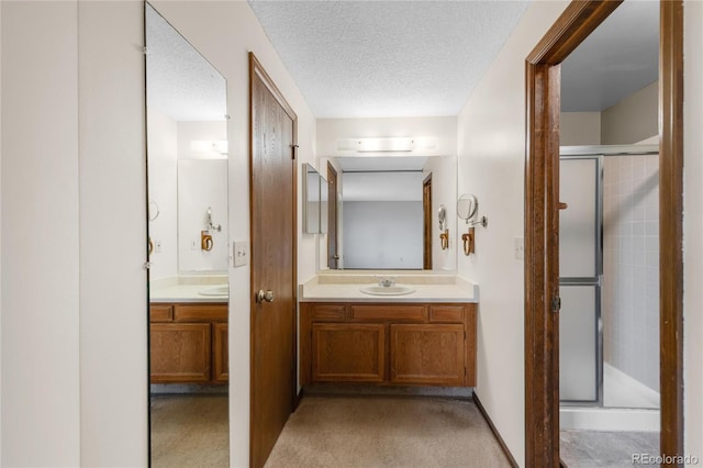 full bath with a shower stall, a textured ceiling, and vanity