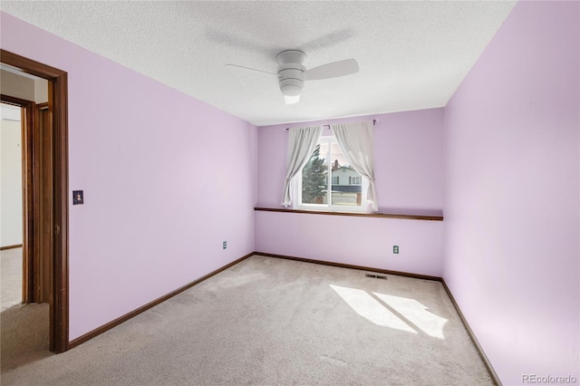 carpeted spare room with visible vents, a ceiling fan, and baseboards