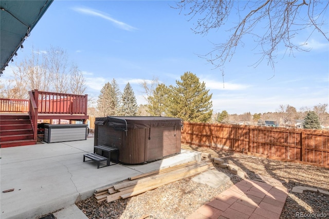 view of patio featuring a wooden deck, a hot tub, and fence