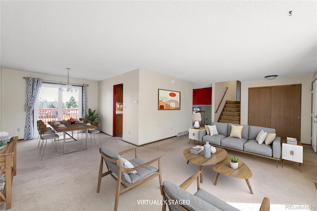 living area with visible vents, baseboards, stairway, light colored carpet, and a textured ceiling