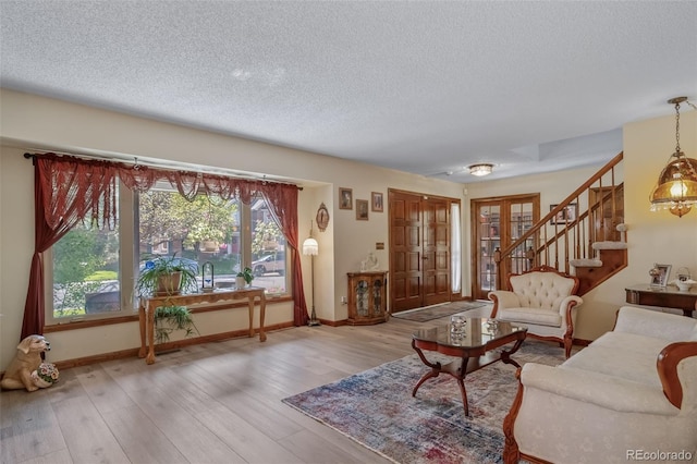 living room with a textured ceiling, baseboards, plenty of natural light, wood finished floors, and stairway