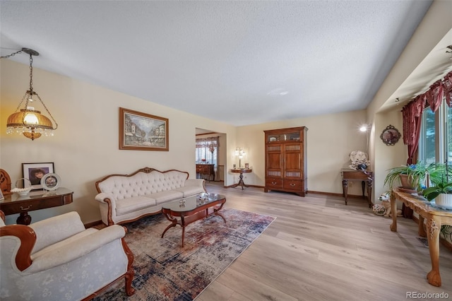 living area with light wood-style floors, baseboards, and a textured ceiling
