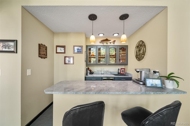 indoor bar featuring hanging light fixtures, a textured ceiling, dark tile patterned flooring, and baseboards