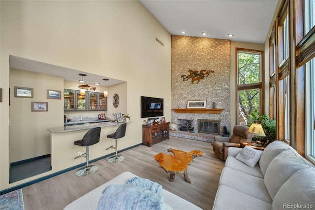living room with high vaulted ceiling, light wood-type flooring, wet bar, baseboards, and recessed lighting