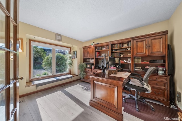 office space featuring a textured ceiling, light wood-style floors, and baseboards