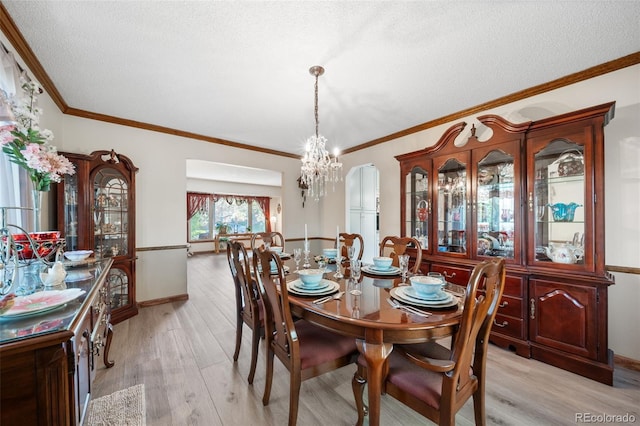 dining room with a chandelier, a textured ceiling, light wood-type flooring, ornamental molding, and baseboards