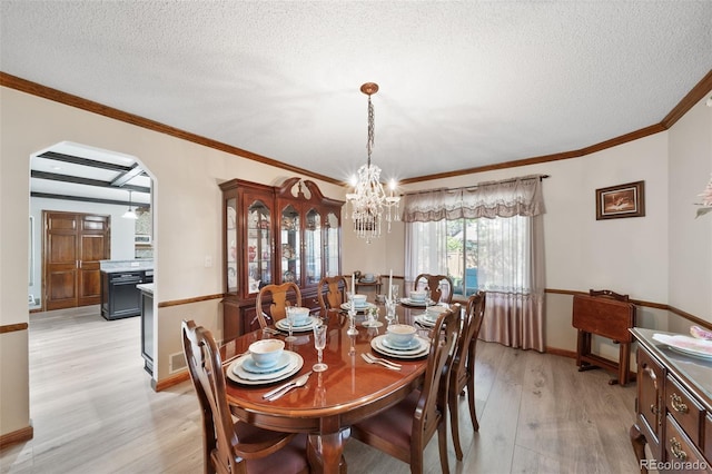 dining room featuring a chandelier, light wood-type flooring, a textured ceiling, crown molding, and baseboards