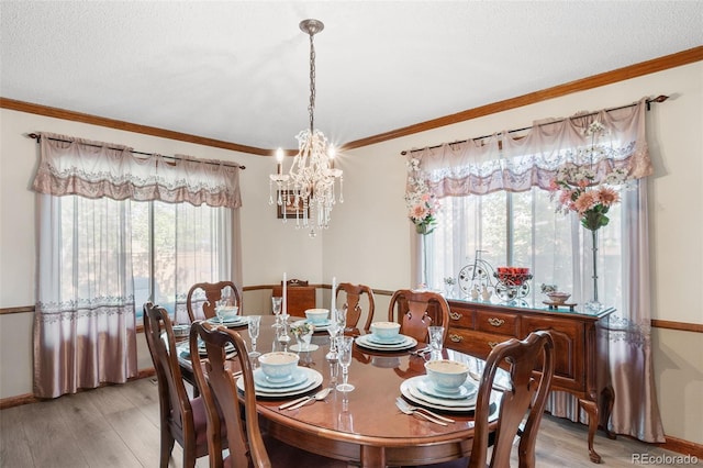 dining area with light wood finished floors, a chandelier, baseboards, crown molding, and a textured ceiling
