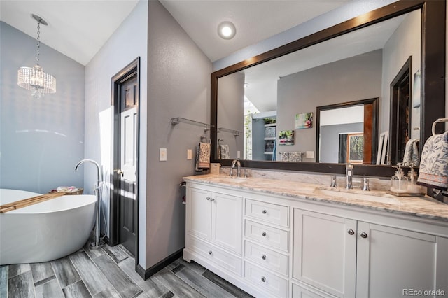 bathroom featuring vaulted ceiling, double vanity, a chandelier, a soaking tub, and wood finish floors
