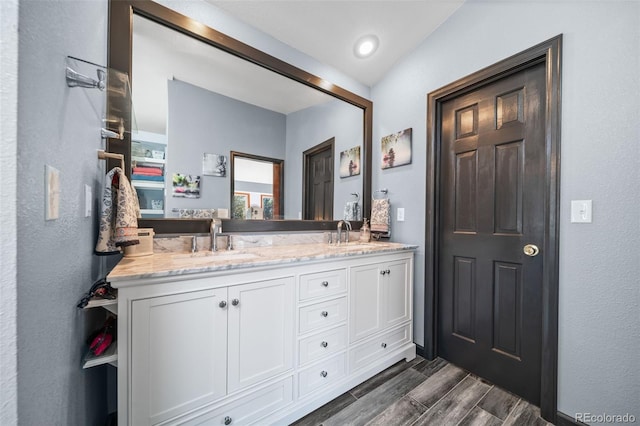 full bathroom featuring double vanity, wood finished floors, and baseboards