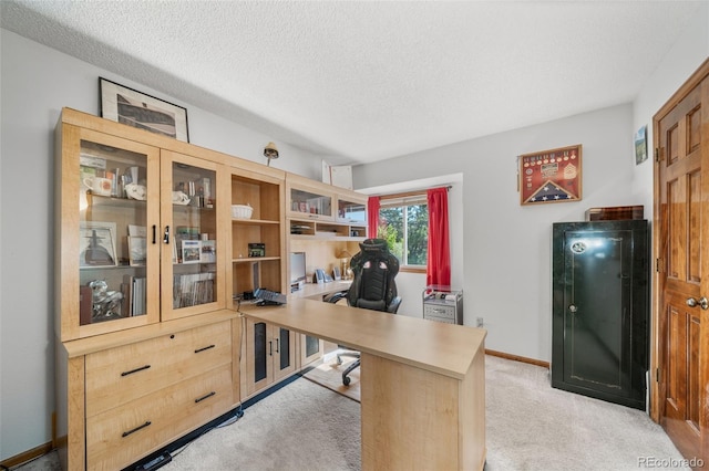 home office featuring light carpet, a textured ceiling, and baseboards