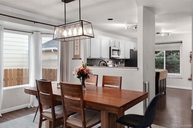 dining space with dark wood-style flooring, baseboards, and crown molding