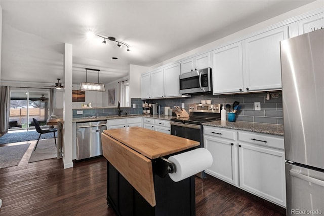 kitchen with butcher block counters, appliances with stainless steel finishes, decorative backsplash, and dark wood-style flooring