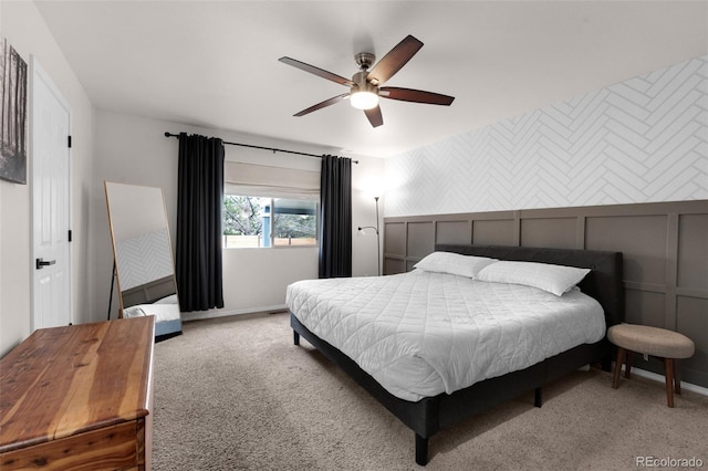 carpeted bedroom featuring a decorative wall, baseboards, and ceiling fan